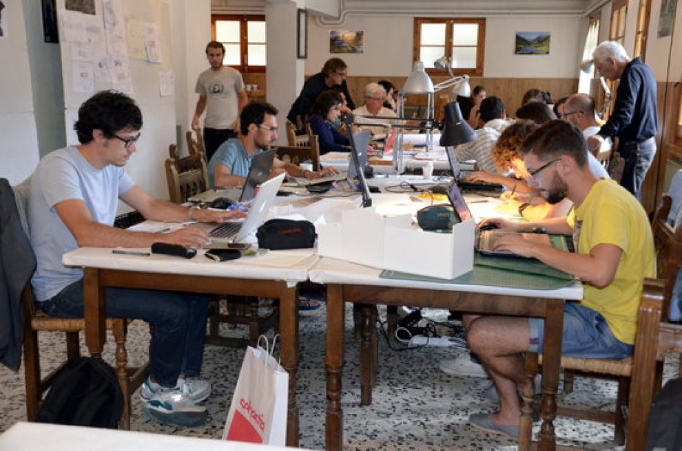Estudiants d'arquitectura treballant en diferents projectes en una sala habilitada a Llessui