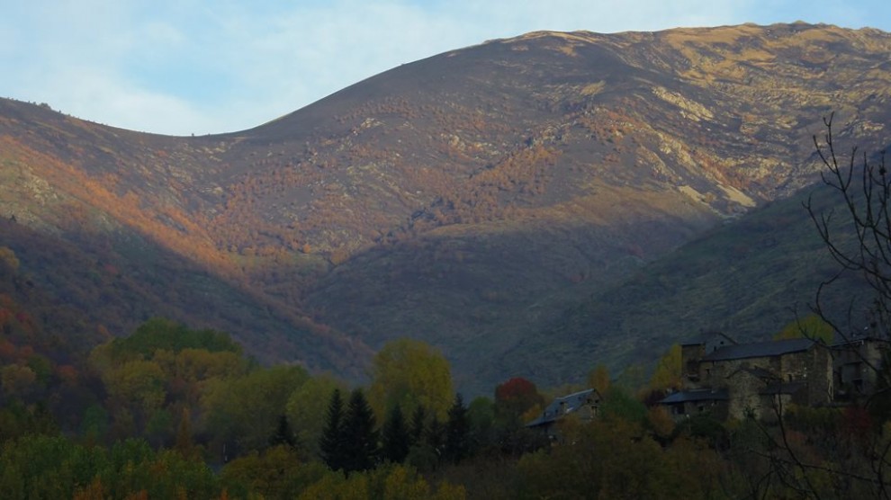 El poble de Cerbi, en primer pla, amb l'estat en què ha quedat la muntanya, al fons
