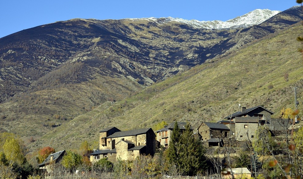 Primer pla del poble de Cerbi amb la muntanya cremada al fons