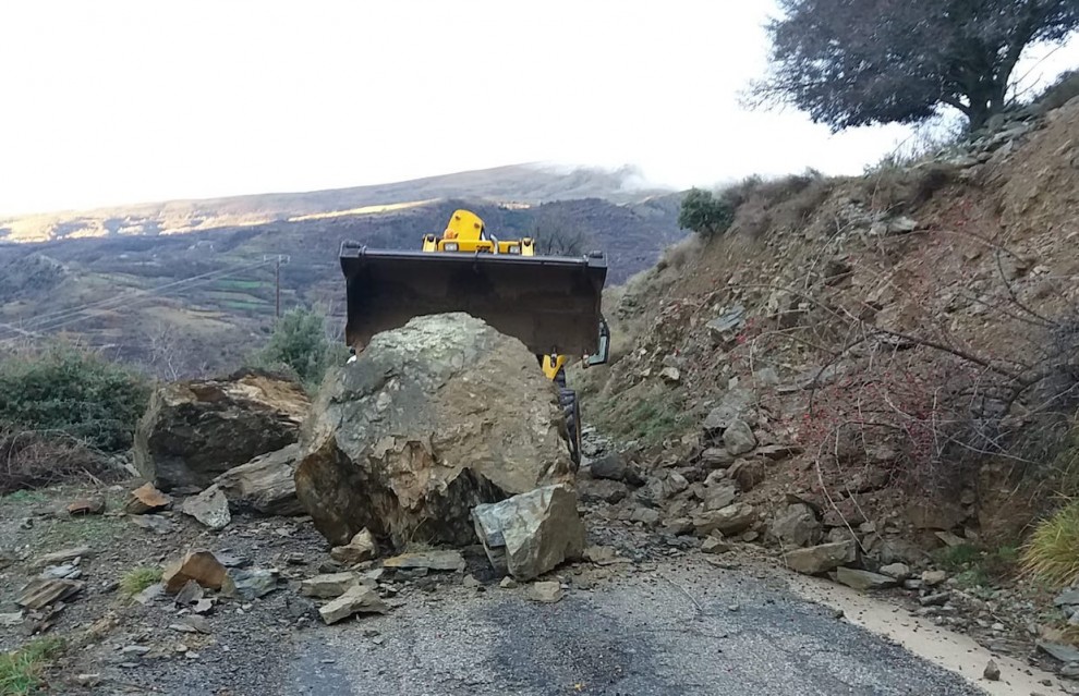 Una màquina excavadora netejant una carretera del municipi de Rialp