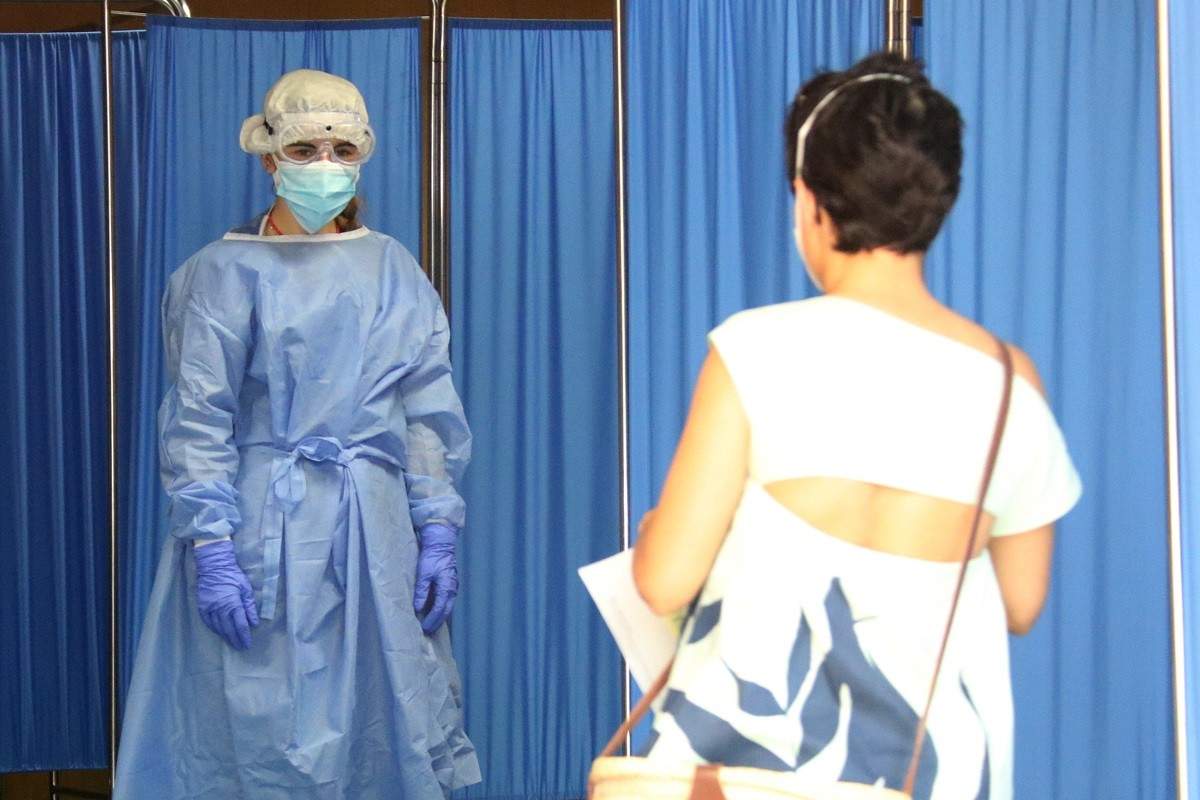 Una sanitària rebent una dona que va a fer-se una PCR