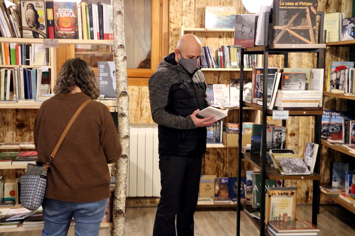 Dos clients fullejant llibres a la nova llibreria