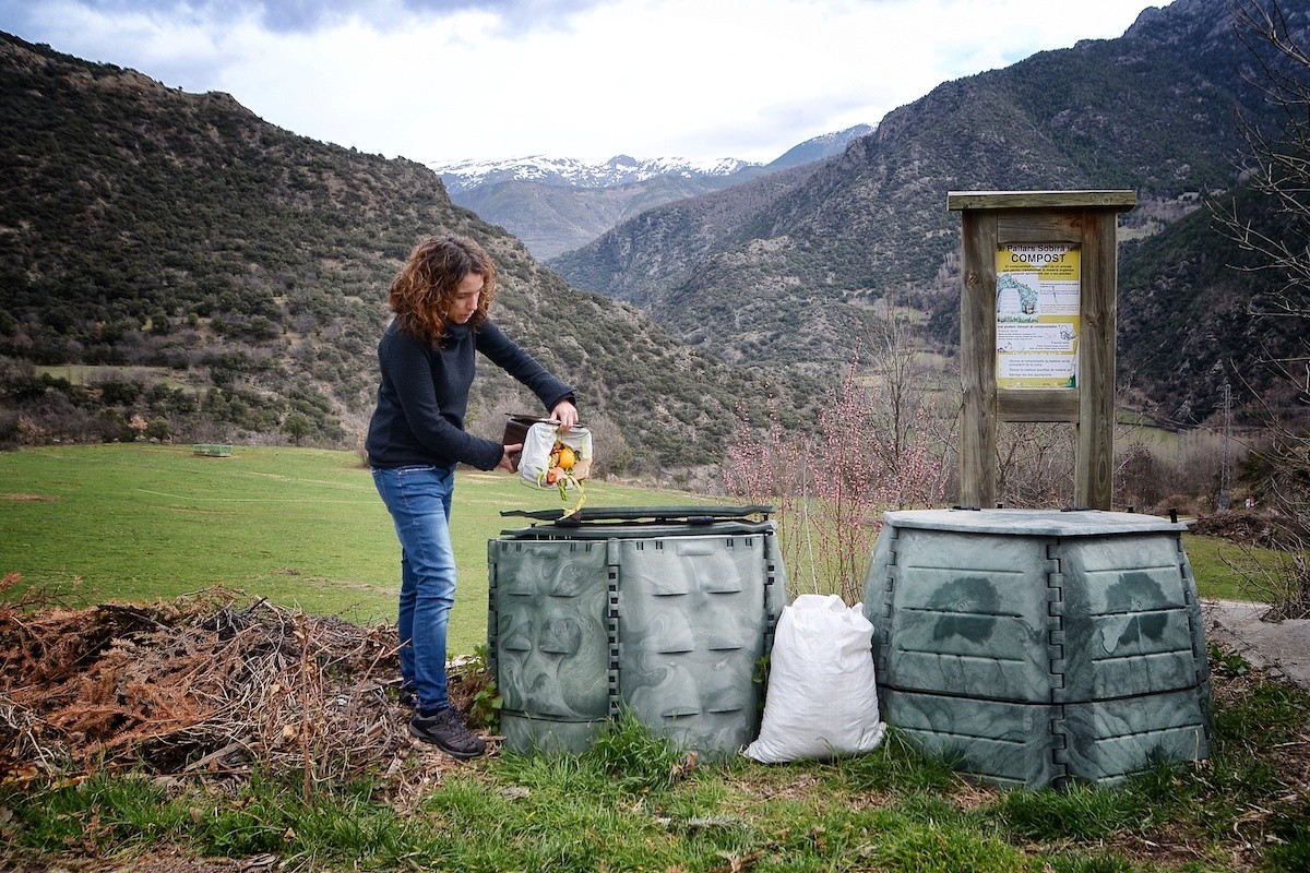 Una veïna de Vall de Cardós llençant residus orgànics en un compostador comunitari