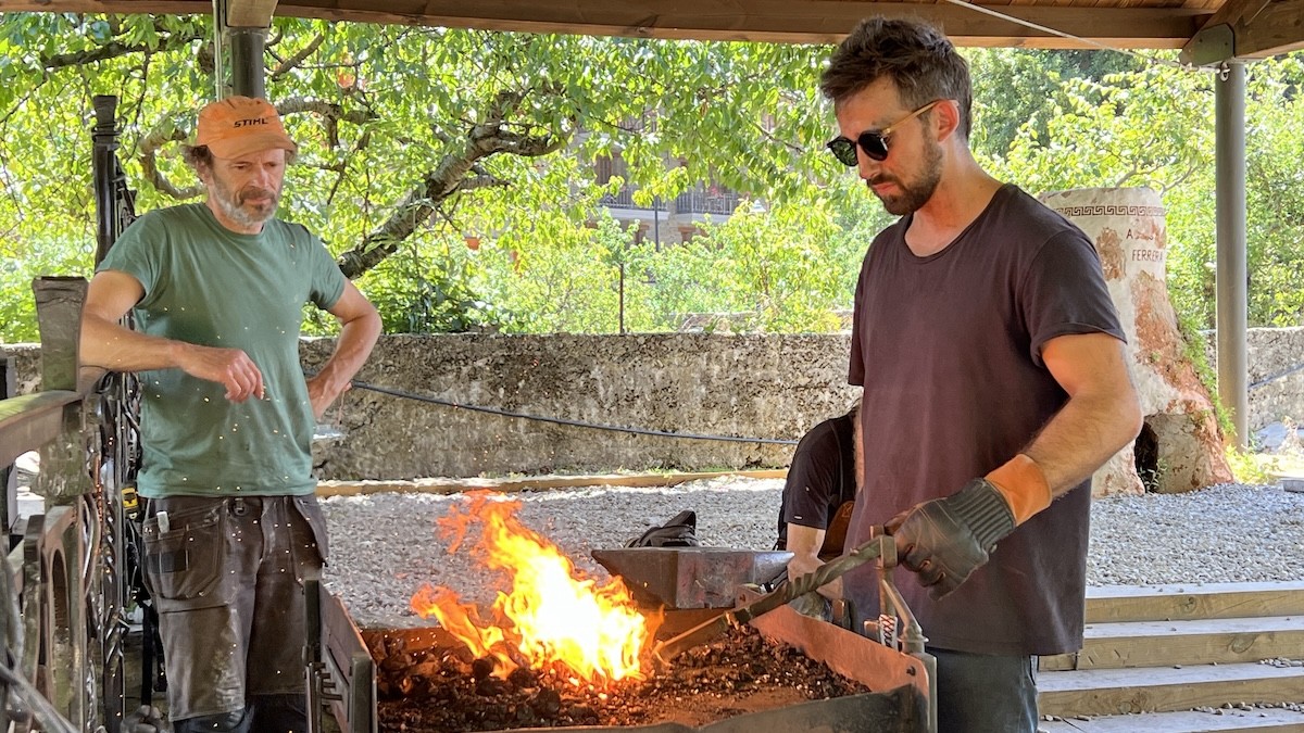 Un alumne del taller de forja d'Alins escalfant el ferro