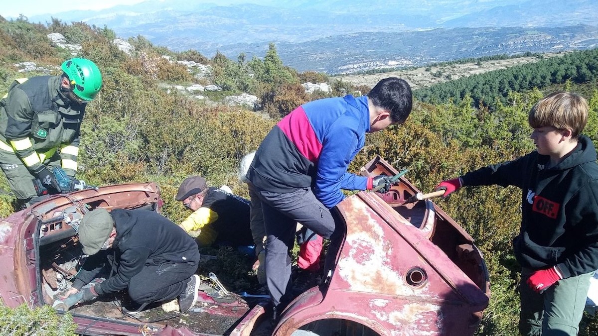 Dos voluntaris i un agent rural al costat d'un vehicle abandonat