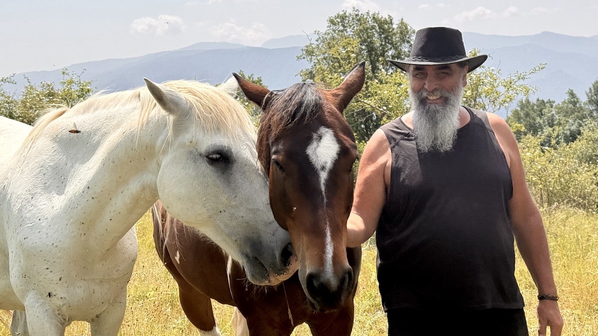 Cases, amb dos dels seus cavalls pasturant amb llibertat a Montcortès