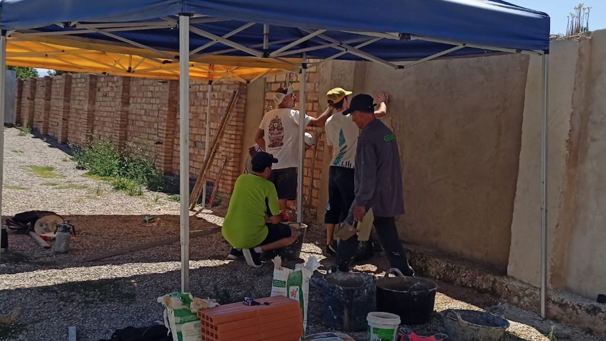 Participants reparant un mur al camp de futbol Pedrasanta durant un dels cursos
