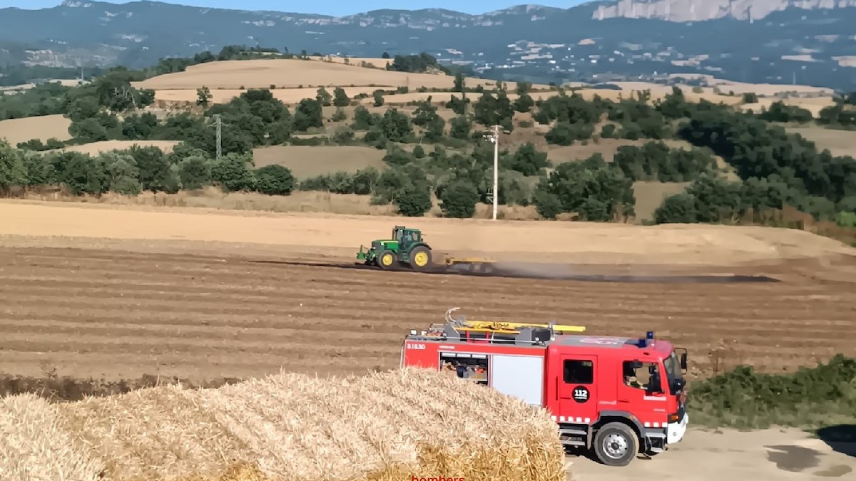 Bombers i un pagès amb el tractor, treballant en l'extinció de l'incendi