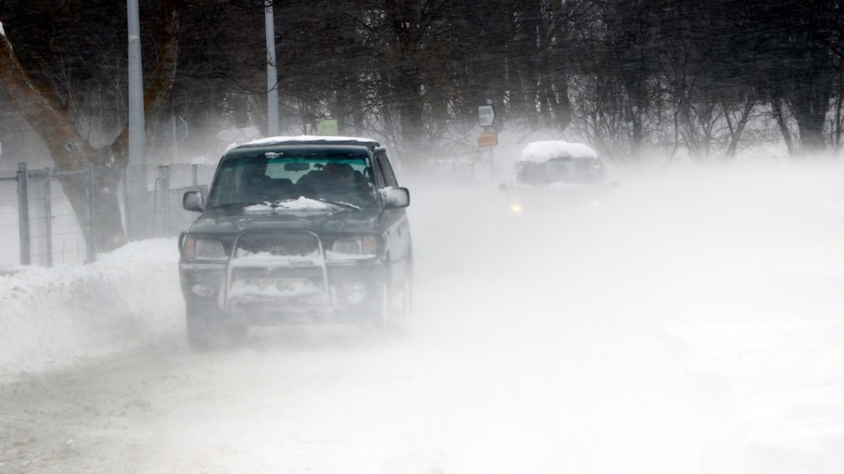 Dos cotxes circulant enmig del vent i la neu, en imatge d'arxiu