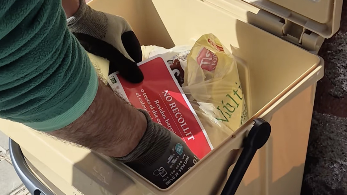 Un operari enganxa un adhesiu en una bossa de reciclatge