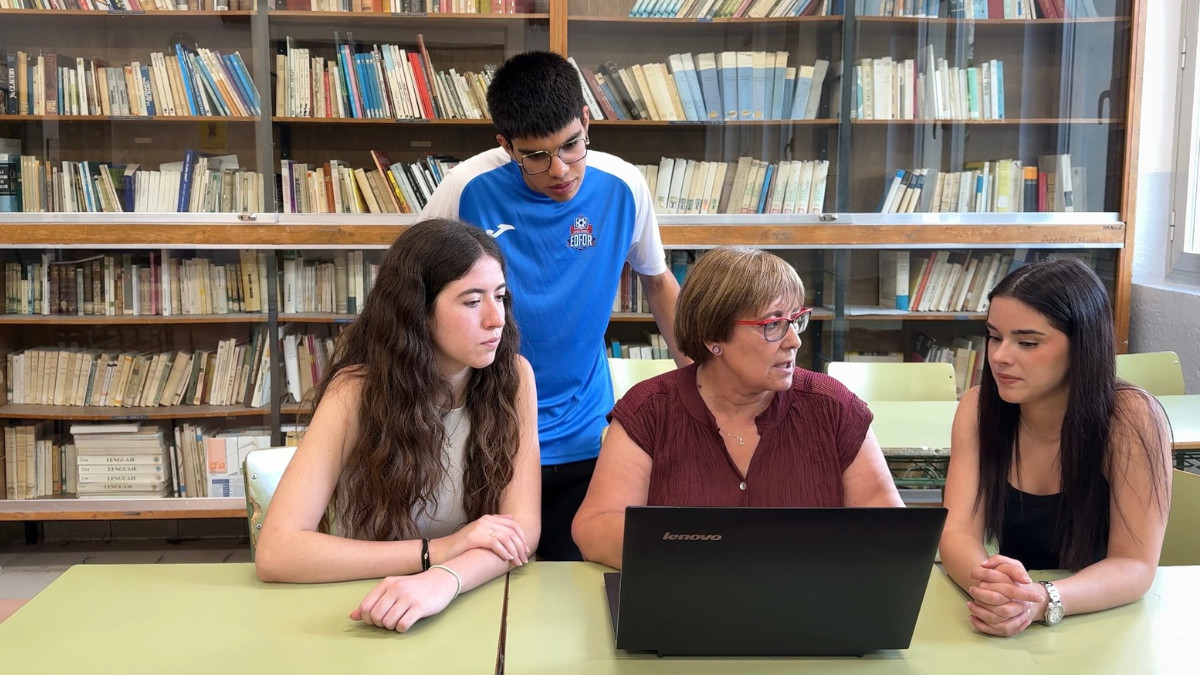 Alumnes i una professora consultant l'oferta de beques