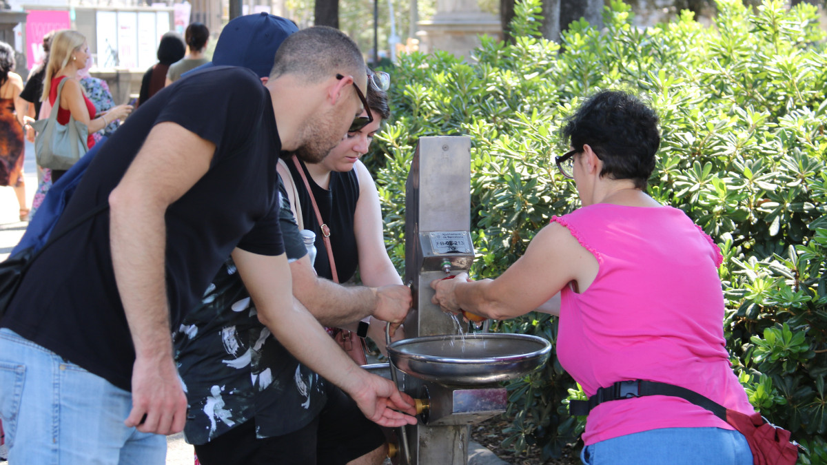 Diverses persones es remullen en una font per apaivagar la calor