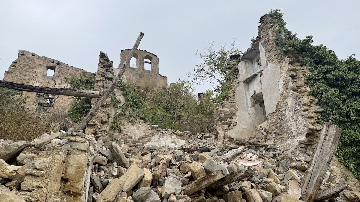 Una casa enrunada i la façana de l'església del poble abandonat de Tendrui Vell